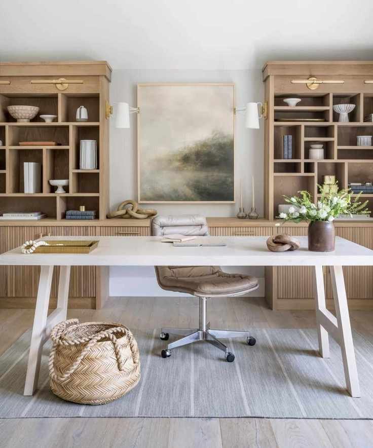 A home office with desk and chair in front of large, light wood bookcases