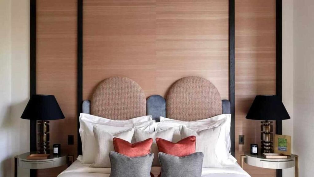 A neutral colored room with an unusually shaped, rounded headboard